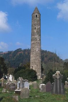 a tall tower with a clock on it's side in the middle of a cemetery