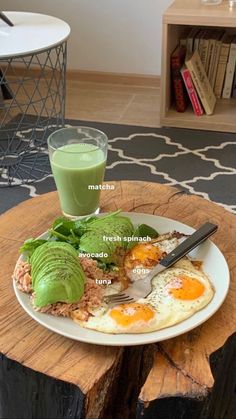 a plate with eggs, avocado and spinach on it next to a glass of green smoothie