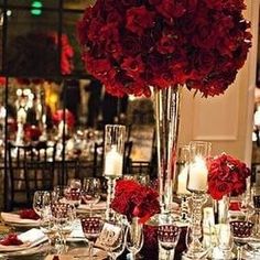 a table set with red roses and candles for a formal dinner or wedding reception in an elegant setting