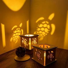 two lit candles sitting on top of a table next to a pine cone and shadow