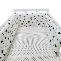 a white crib bed with black stars on the sheets and bottom sheet, in front of a white background