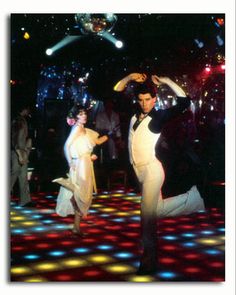 two people dancing on a dance floor with disco lights in the background