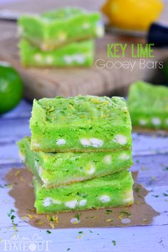 three pieces of green cake sitting on top of a cutting board next to lemons