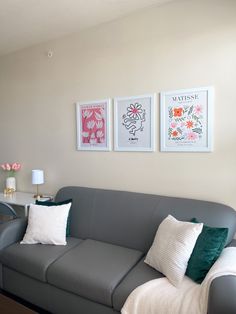 a living room with gray couches and three pictures on the wall above each couch