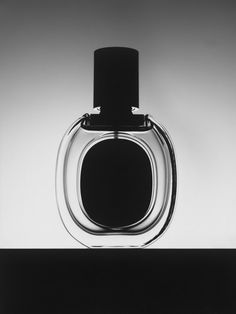 an empty glass bottle sitting on top of a black table next to a white wall