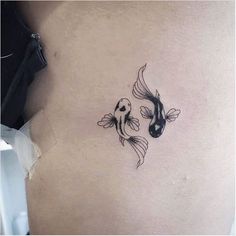 two goldfish tattoo on the back of a woman's left side ribcage