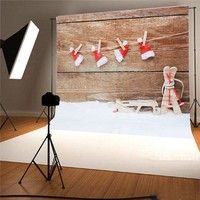 a photo shoot with a teddy bear and santa hats hanging on the clothes line in front of a wooden wall