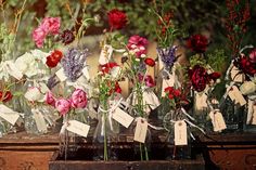 several vases with flowers in them sitting on a table next to some cards and tags