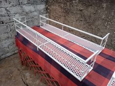 a red and black checkered table cloth with white metal rails on it in front of a stone wall