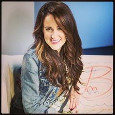 a woman sitting on top of a white couch next to a wall with writing on it