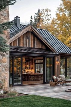 a wooden house with glass doors and windows on the outside, surrounded by grass and trees