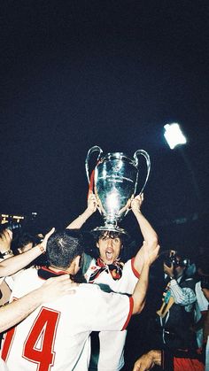 two soccer players are holding the trophy in front of their heads while others look on