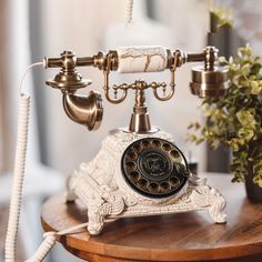 an old fashioned phone sitting on top of a wooden table next to a potted plant