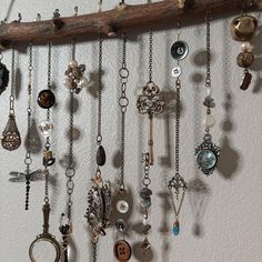 a bunch of necklaces hanging from a wooden stick on a wall next to a white wall