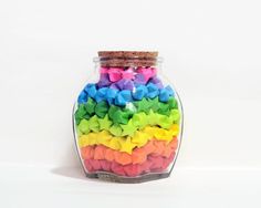 a jar filled with lots of different colored paper stars on top of a white surface