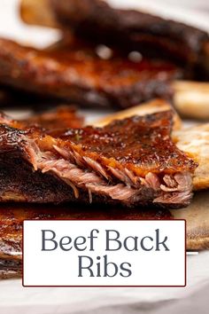 some ribs are sitting on a cutting board next to other meats and bread slices