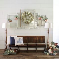 a wooden bench sitting in front of a white wall with wreaths on the wall