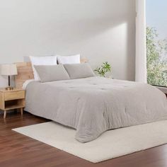 a large bed sitting on top of a hard wood floor next to a window in a bedroom