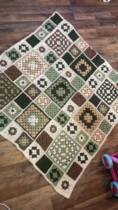 a crocheted granny blanket on the floor next to a pair of pink shoes