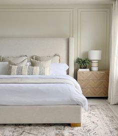 a bed with white linens and pillows in a neutral bedroom, along with two nightstands