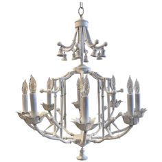 a white chandelier with six candles hanging from it's center and four arms