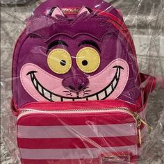 Brand New Never Opened "We're All Mad Here." Mad About This Marvelous Disney Alice In Wonderland Cheshire Cat Mini-Backpack, That Is! Made Of Colorful Faux Leather And Measuring About 10 1/2-Inches Tall X 9-Inches Wide X 4 1/2-Inches Deep, It Features Zipper Closure And A Zippered Front Pocket, A Matching Themed Lining, And Adjustable Straps, Plus Applique, Printed, And Embroidered Details, Enamel Zipper Pulls And A Tail And Glow-In-The-Dark Face! Order Yours Before The Cheshire Cat Fades Away! Disney Purple Backpack, Purple Disney Backpack, Fun Purple Backpack, Purple Backpack For Disney Trips, Loungefly Purse, Dark Face, Alice In Wonderland Cheshire Cat, Wonderland Cheshire Cat, The Cheshire Cat