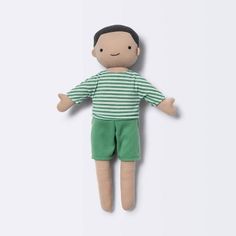 a small doll with green shorts and a striped shirt is posed on a white background