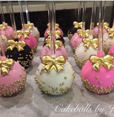 there are many pink and white cake balls with gold bows on them, all in different colors