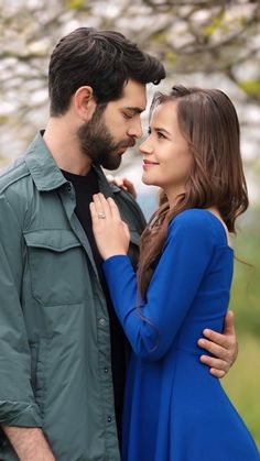 a man and woman standing next to each other in front of a tree with flowers