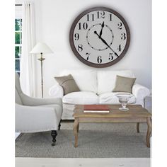 a living room with a clock on the wall and white furniture in front of it