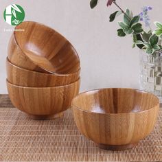 three wooden bowls sitting on top of a table next to a vase filled with flowers