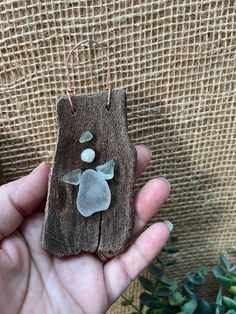 a hand holding a piece of wood with sea glass on it