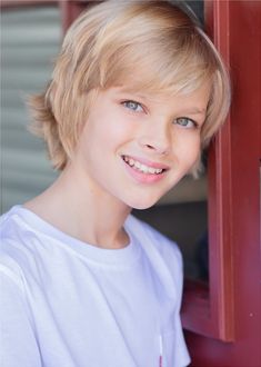 a close up of a person wearing a white shirt and smiling at the camera with blue eyes