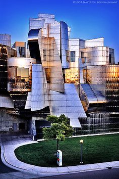 the exterior of an art museum with grass and trees in front of it at dusk