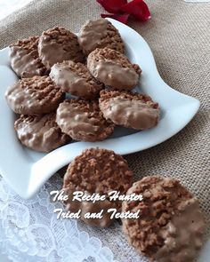 cookies with chocolate frosting on a white plate and red rose in the background, sitting on a lace tablecloth