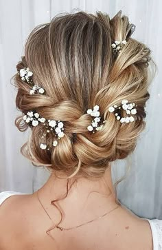 the back of a woman's head with flowers in her hair, wearing a white dress