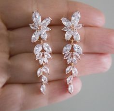 a pair of earrings in the palm of someone's hand, with diamonds on them