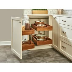 an open cabinet in the corner of a kitchen with drawers and spice jars on it