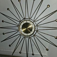 a clock that is hanging from the ceiling with nails on it's face and hands