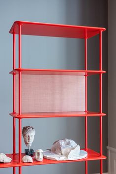 a red shelf with two sculptures on it