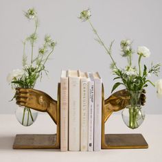 two vases filled with flowers and books on top of a table