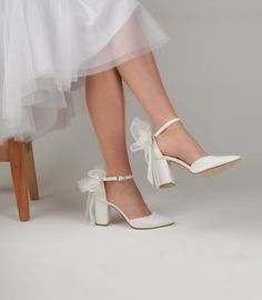 a woman's legs wearing white shoes with bows