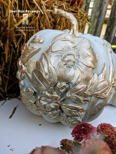 a white pumpkin sitting on top of a table next to some dried grass and flowers