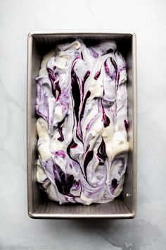 a square metal container filled with white and purple food