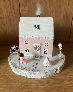 a small pink and white house sitting on top of a wooden table