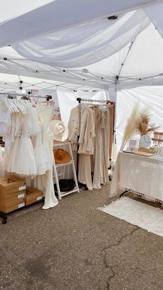 an open tent with clothes hanging on racks