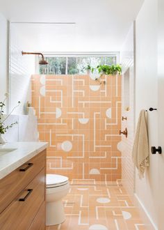 a bathroom with an orange and white tiled wall