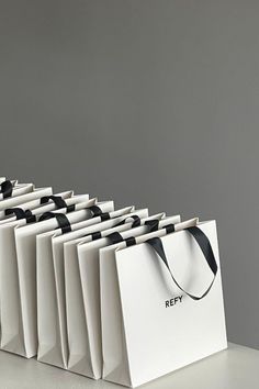 several white shopping bags with black handles are lined up in a row on a table