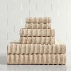 towels stacked on top of each other in front of a white brick wall and floor