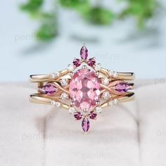 a pink diamond ring on top of a white surface with greenery in the background